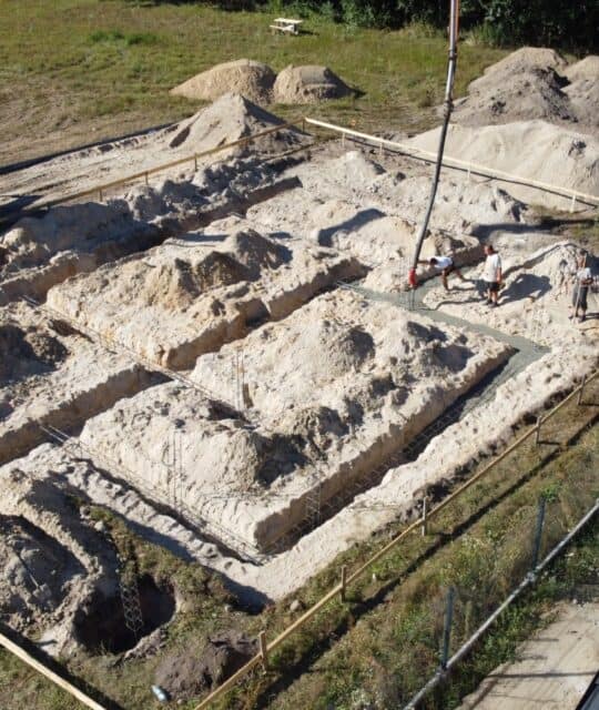 Ekologiczne fundamenty pod budowę, fundamenty w trakcie prac, budowa wczesnej struktury domu, budowlane fundamenty z piasku i cementu, prace archeologiczne i budowlane na placu budowy, fundamenty pod nowoczesne domy stawia firma Stavia.